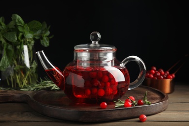 Photo of Tasty hot cranberry tea and fresh ingredients on wooden table