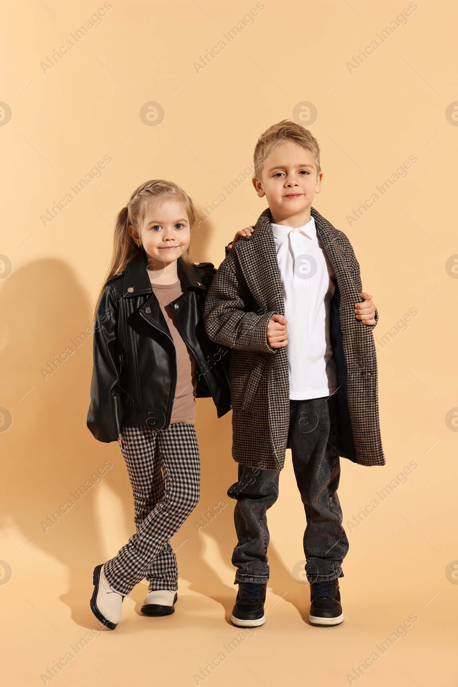 Photo of Fashion concept. Stylish children posing on pale orange background