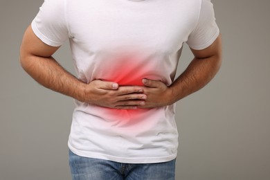 Image of Man suffering from stomach pain on grey background, closeup