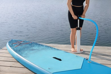 Photo of Woman pumping up SUP board on pier, closeup