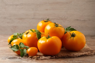 Fresh ripe yellow tomatoes with leaves on wooden table