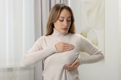 Photo of Mammology. Young woman doing breast self-examination at home