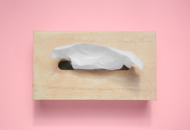 Photo of Wooden holder with paper tissues on pink background, top view