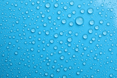 Water drops on light blue background, top view