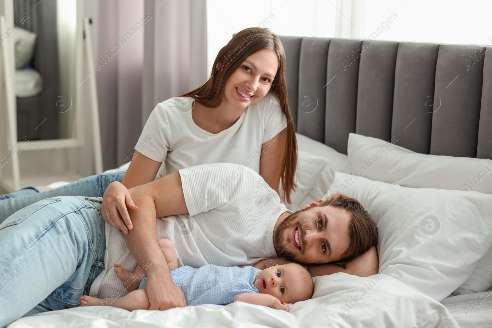 Photo of Happy family. Parents with their cute baby on bed indoors