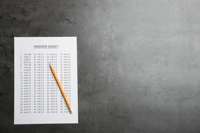 Photo of Answer sheet and pencil on grey background, top view with space for text