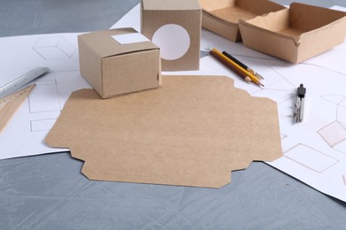 Photo of Creating packaging design. Drawings, boxes and stationery on blue textured table, closeup