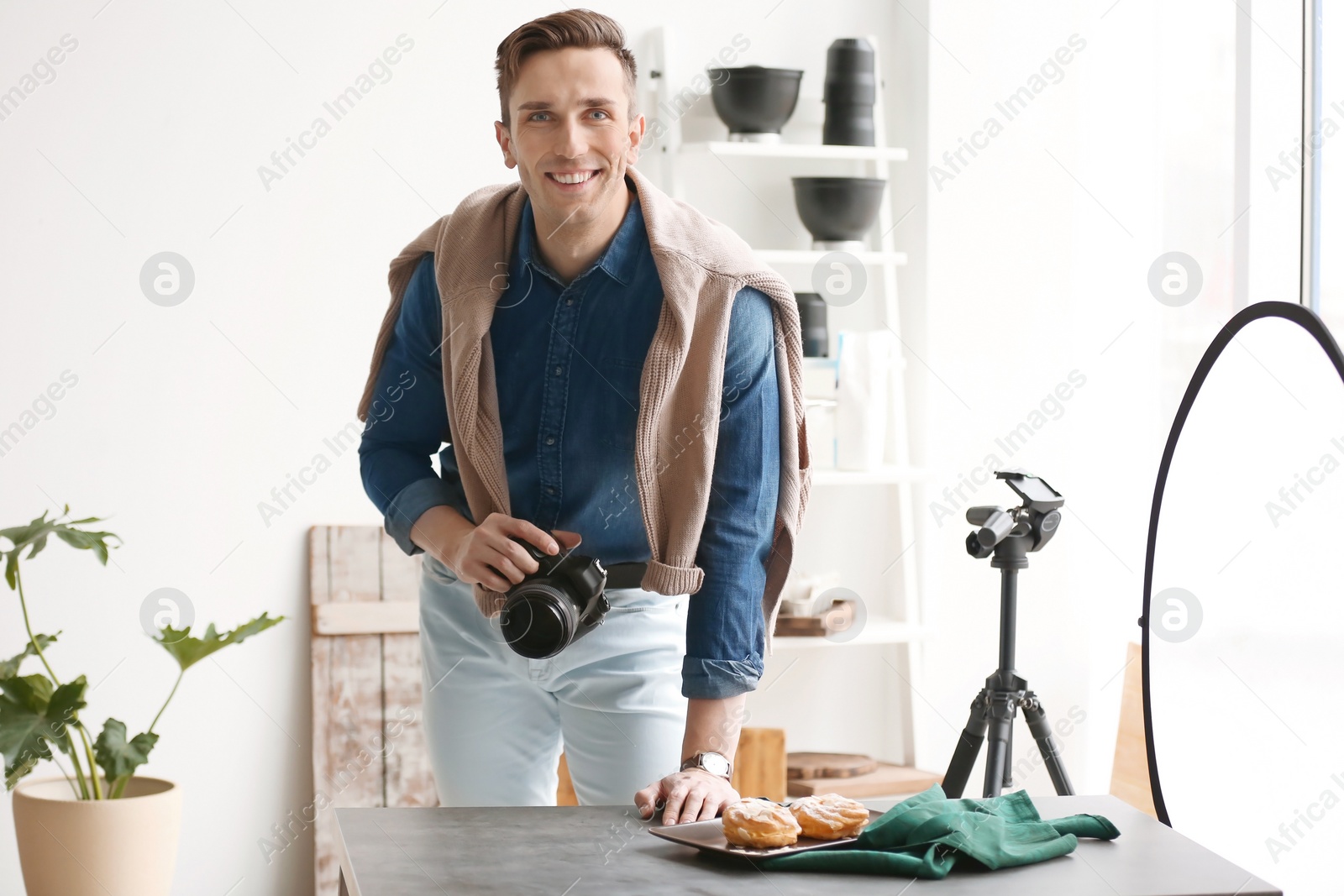 Photo of Young man with professional camera in photo studio