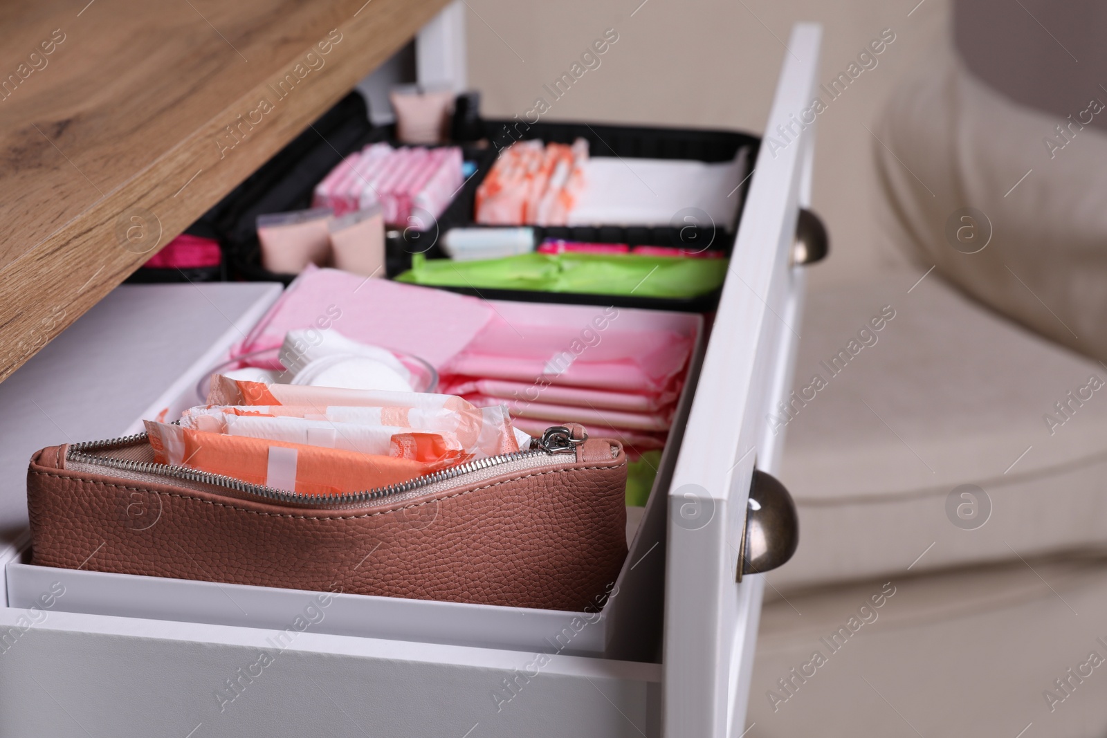 Photo of Open cabinet drawer with menstrual pads and tampons in room, closeup