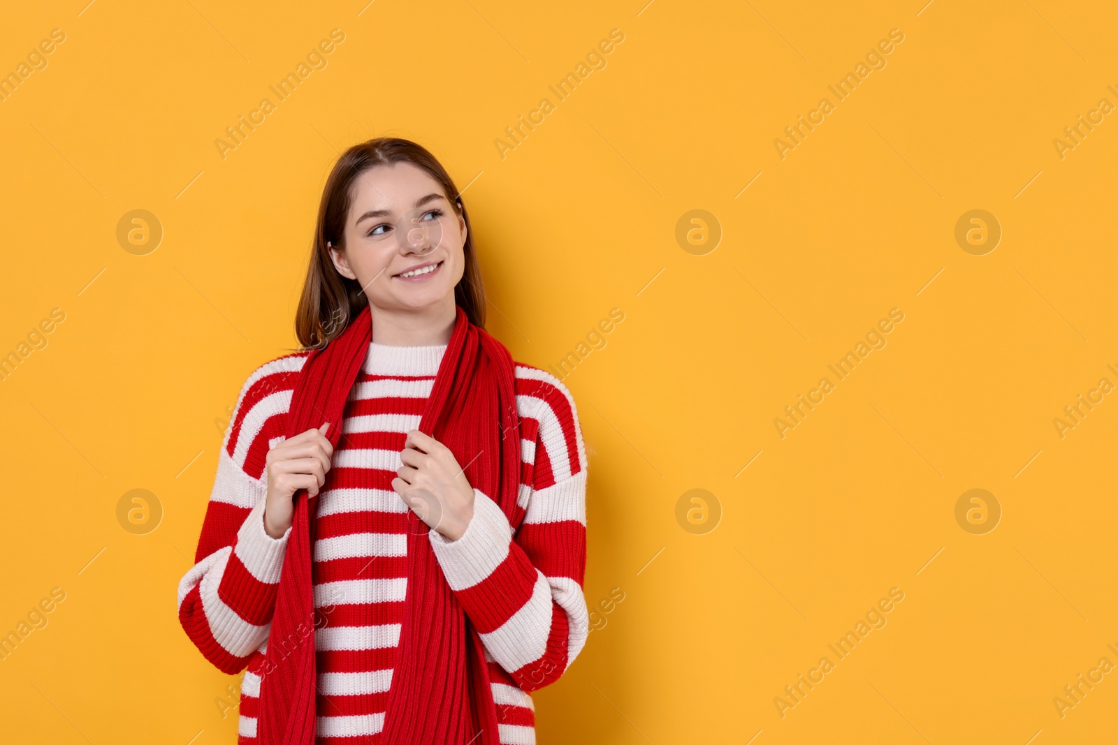 Photo of Beautiful woman in warm scarf on yellow background, space for text