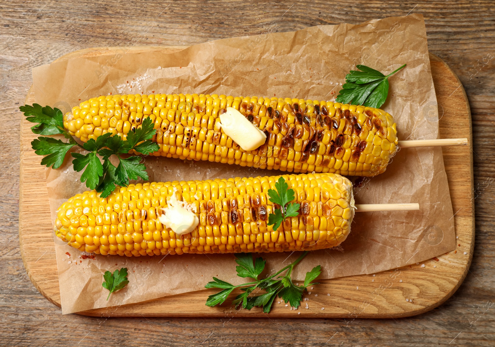 Photo of Tasty grilled corn on wooden table, top view