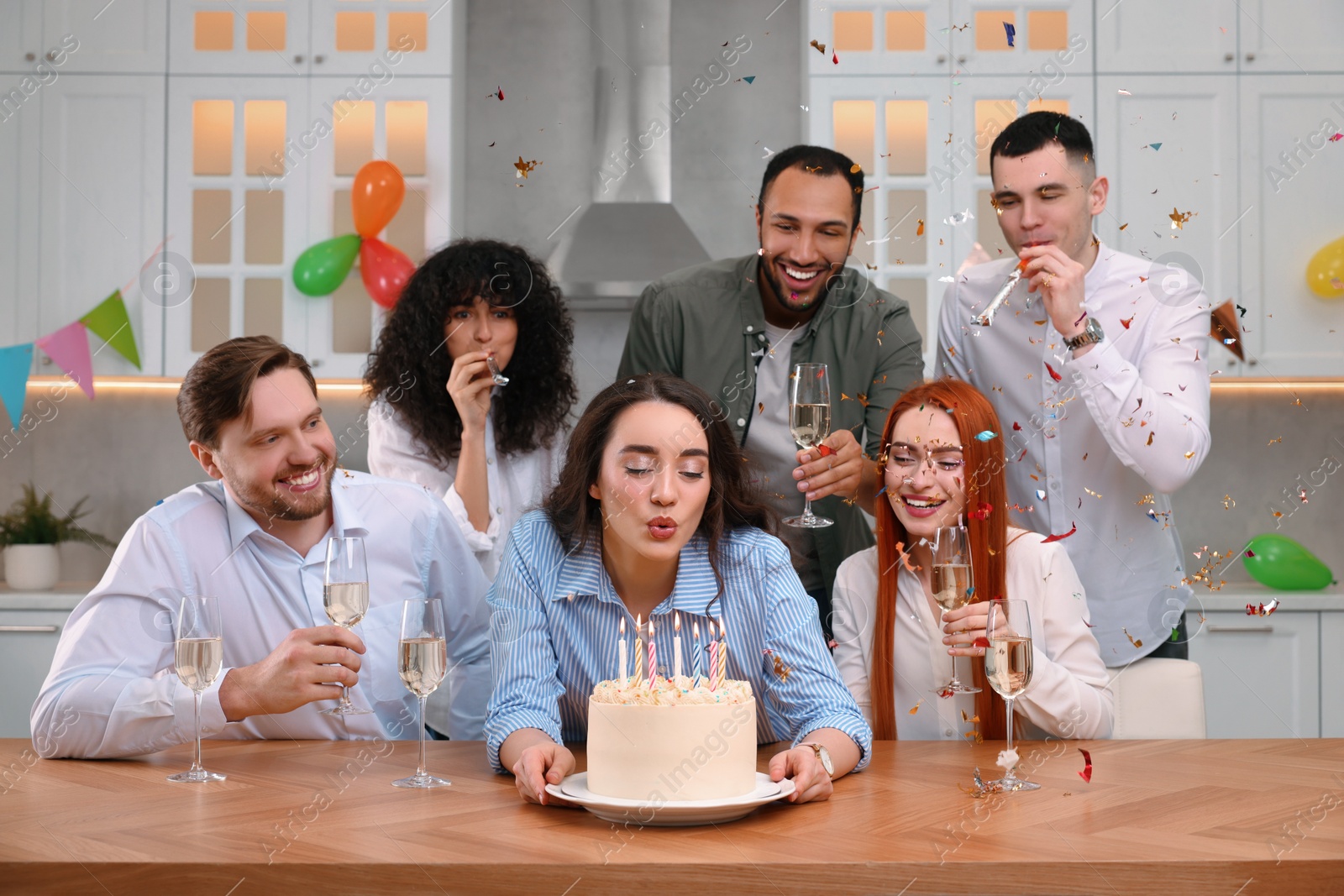 Photo of Happy friends with tasty cake celebrating birthday in kitchen