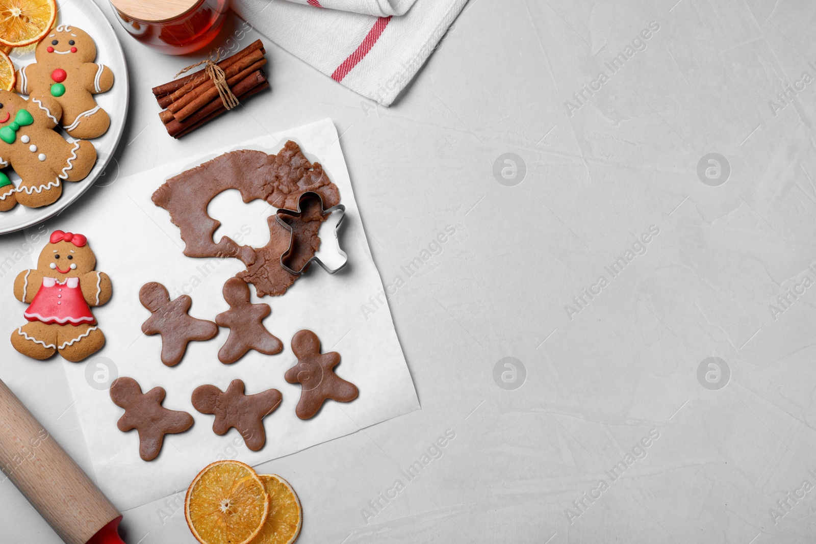Photo of Flat lay composition with homemade gingerbread man cookies on light table, space for text