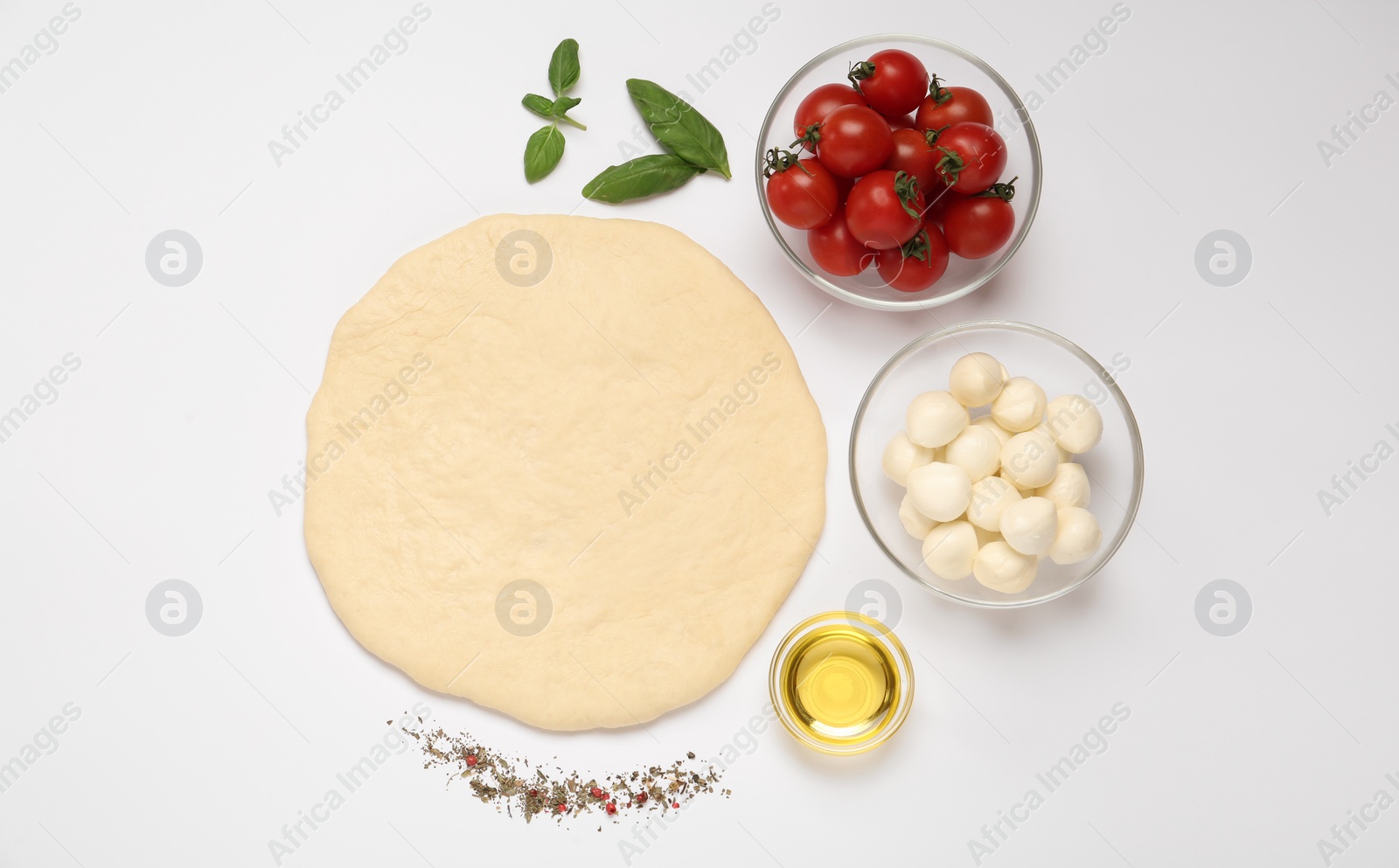 Photo of Raw dough and other ingredients for pizza on white background, top view