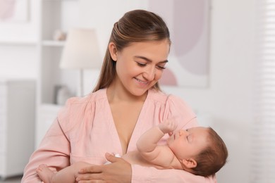 Mother holding her cute newborn baby in child's room