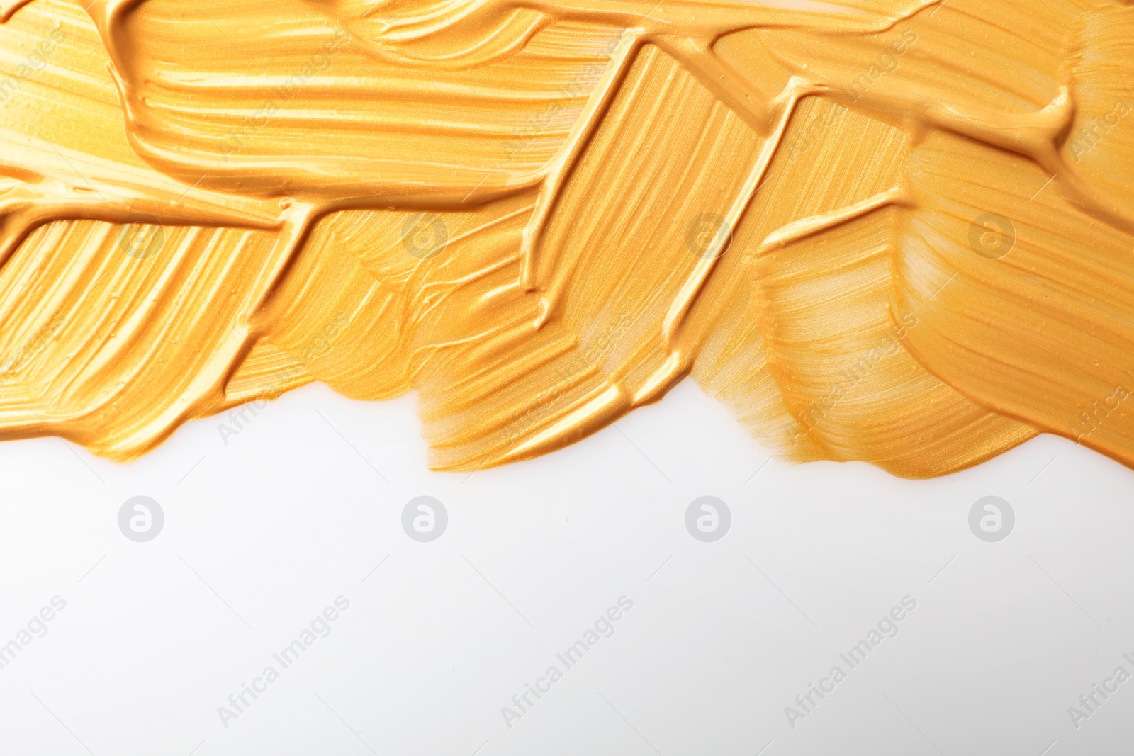 Photo of Strokes of gold paint isolated on white, top view