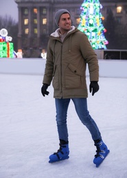 Image of Happy man skating at outdoor ice rink