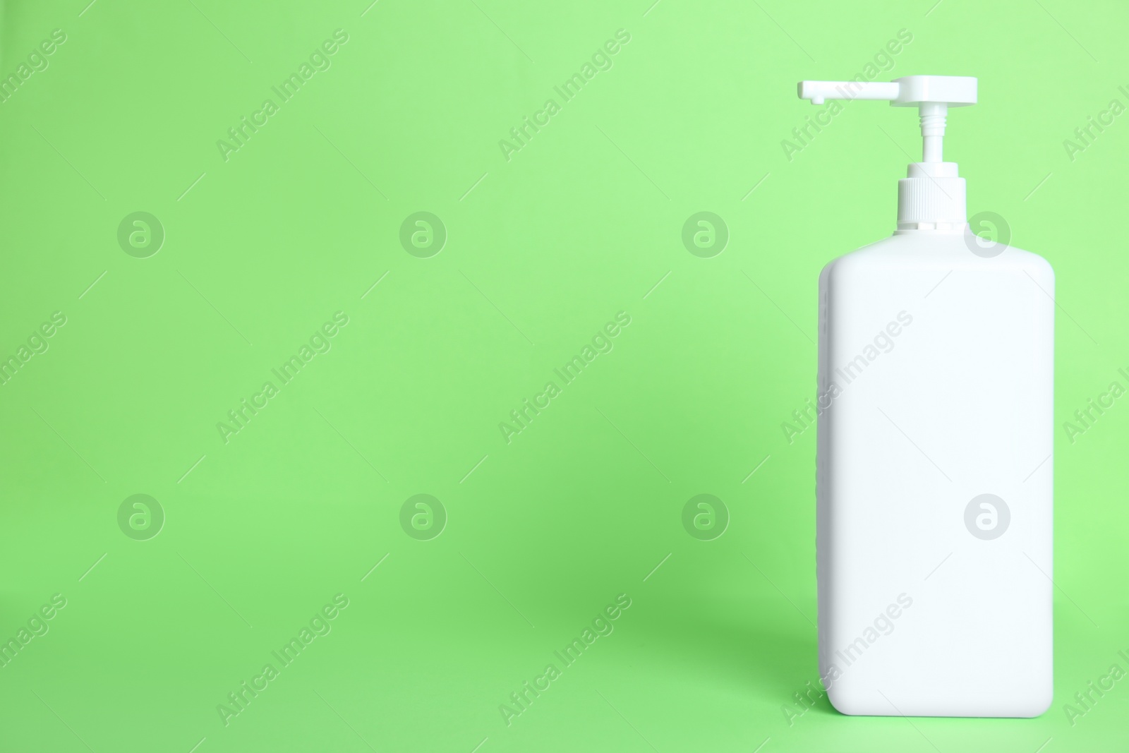 Photo of Dispenser bottle with antiseptic gel on green background. Space for text