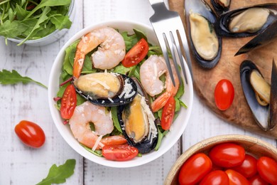 Photo of Bowl of delicious salad with seafood on white wooden table, flat lay