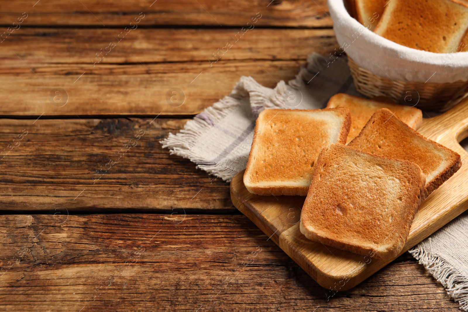 Photo of Slices of tasty toasted bread on wooden table, space for text