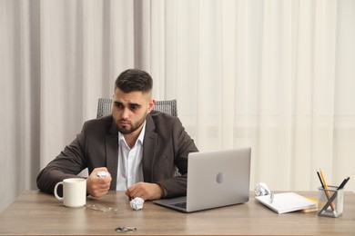 Photo of Sad businessman sitting at table in office