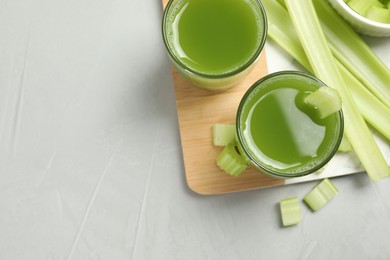 Photo of Celery juice and fresh vegetables on light gray table, flat lay. Space for text