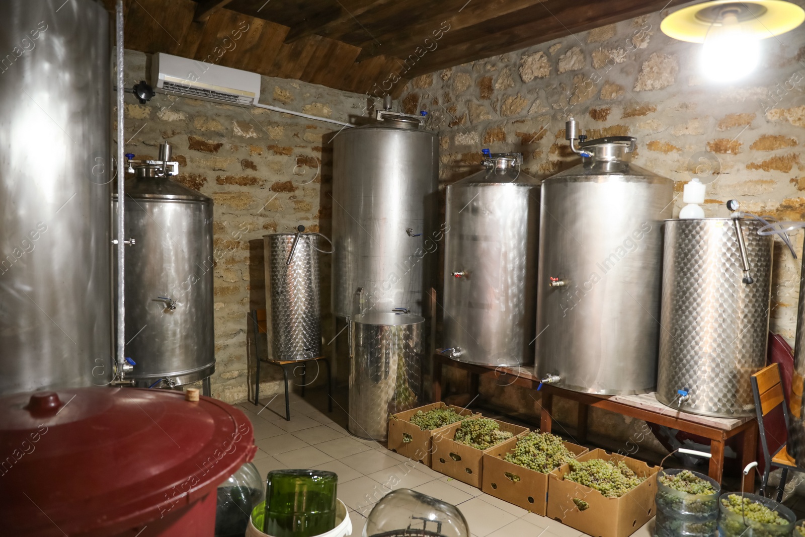 Photo of Steel tanks for wine fermentation and fresh grapes at factory