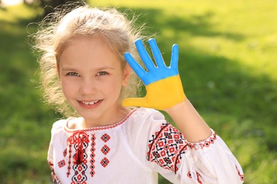 Photo of Little girl with hand painted in Ukrainian flag colors outdoors. Love Ukraine concept