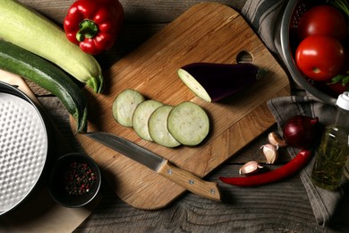 Cooking delicious ratatouille. Different fresh vegetables, spices and knife on wooden table, flat lay