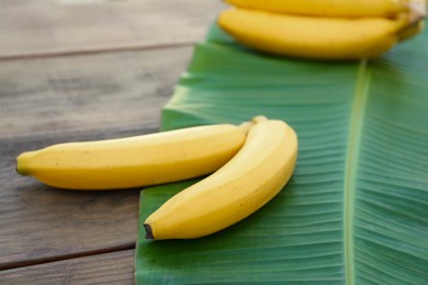 Delicious bananas and green leaf on wooden table