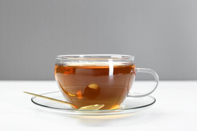 Glass cup of tea and spoon on white table