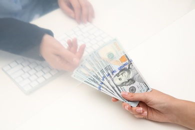 Photo of Woman giving money to teller at cash department window, closeup