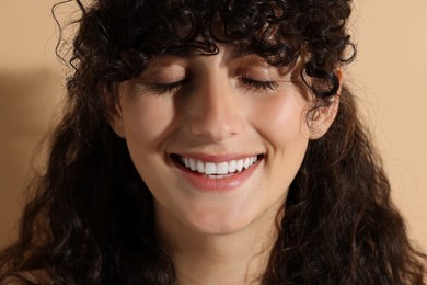 Portrait of beautiful young woman on beige background, closeup