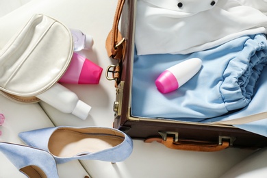 Photo of Vintage suitcase with deodorants and clothes indoors, closeup view