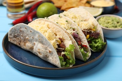 Photo of Delicious tacos with meat and vegetables on light blue table, closeup