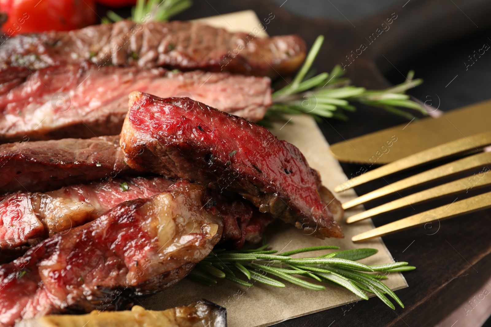 Photo of Delicious grilled beef with rosemary and cutlery on table, closeup