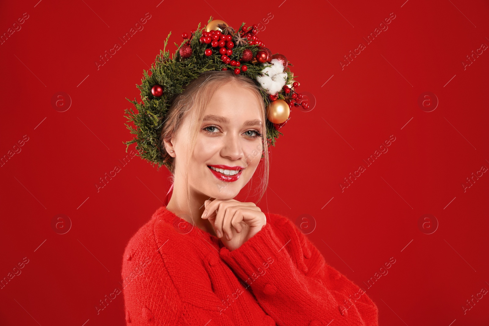 Photo of Beautiful young woman wearing Christmas wreath on red background