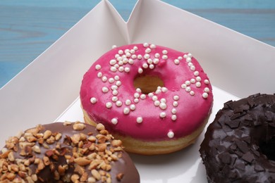 Photo of Different tasty glazed donuts in box, closeup