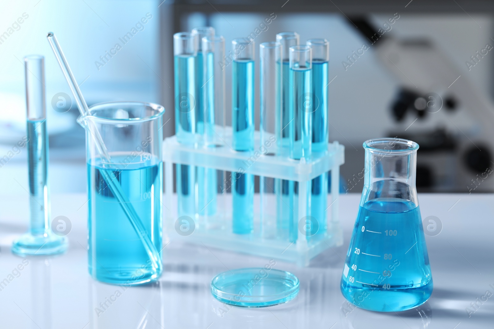 Photo of Different glassware and test tubes with light blue liquid on table in laboratory