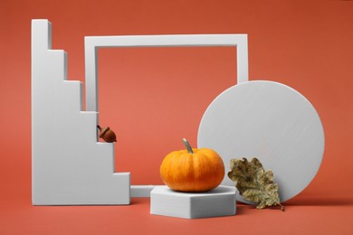 Photo of Stylish presentation for product. White geometric figures and autumn decoration on coral background
