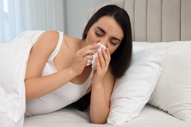 Photo of Sick young woman with tissue in bed at home