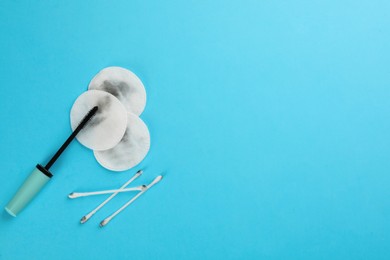 Photo of Dirty cotton pads, swabs with mascara on turquoise background, flat lay. Space for text