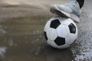 Photo of Man with soccer ball near puddle outdoors, closeup. Space for text