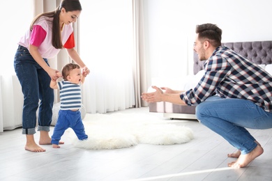 Photo of Happy family playing and baby learning to walk at home