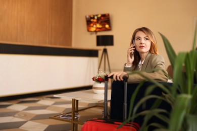 Beautiful woman talking on phone while waiting in hotel hall