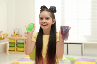 Photo of Little girl playing with slime in room