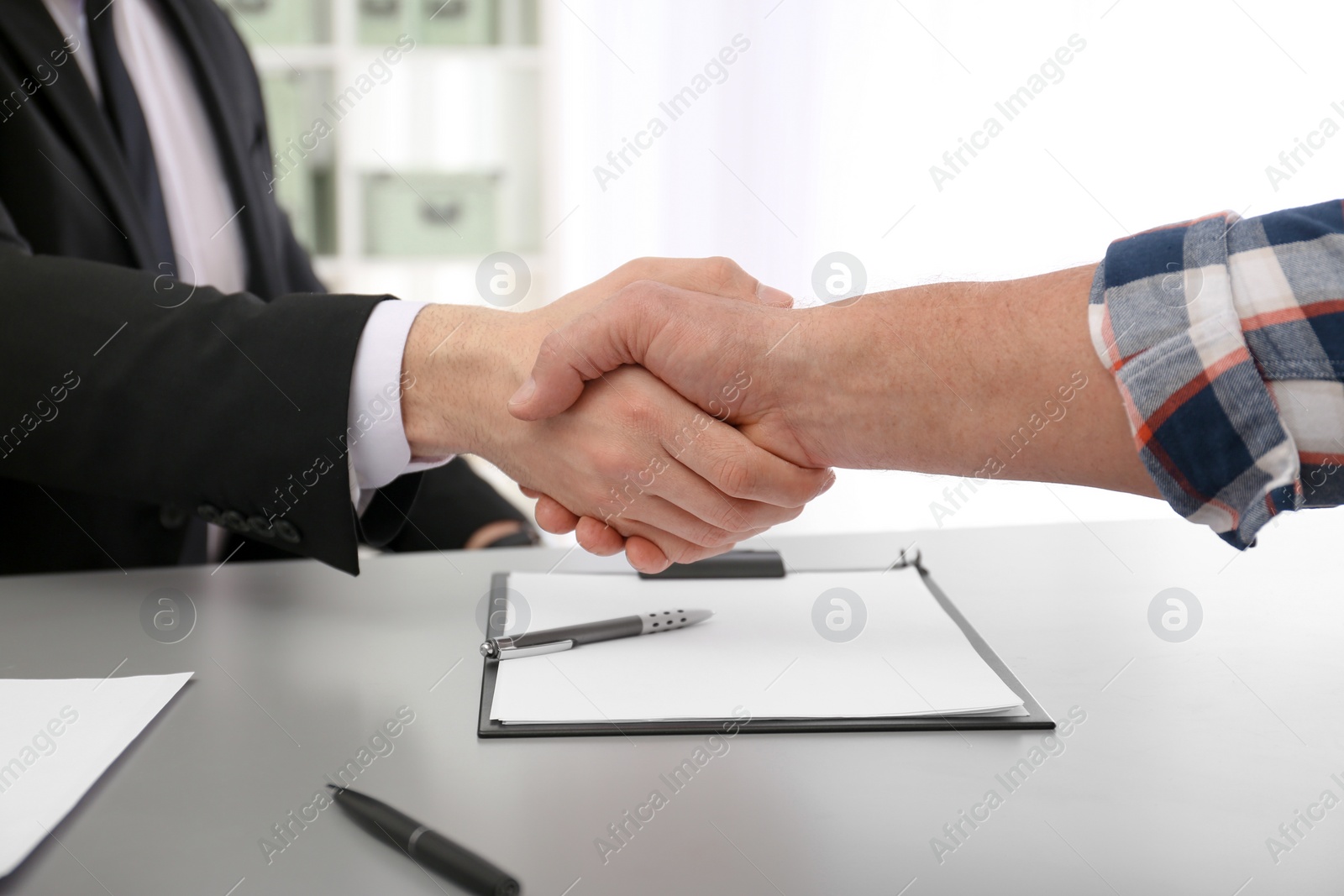 Photo of Lawyer shaking hands with client in office, closeup