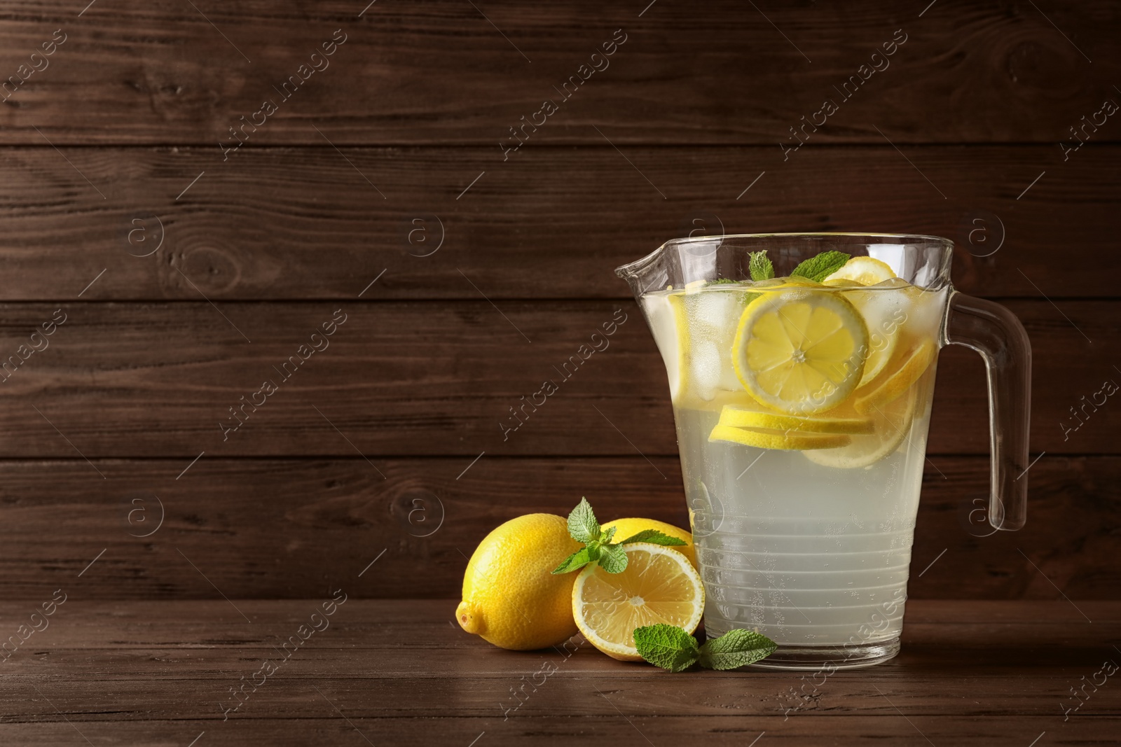 Photo of Glass jug with natural lemonade on wooden table