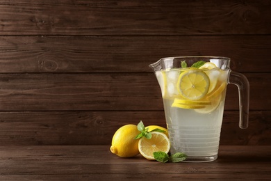 Glass jug with natural lemonade on wooden table