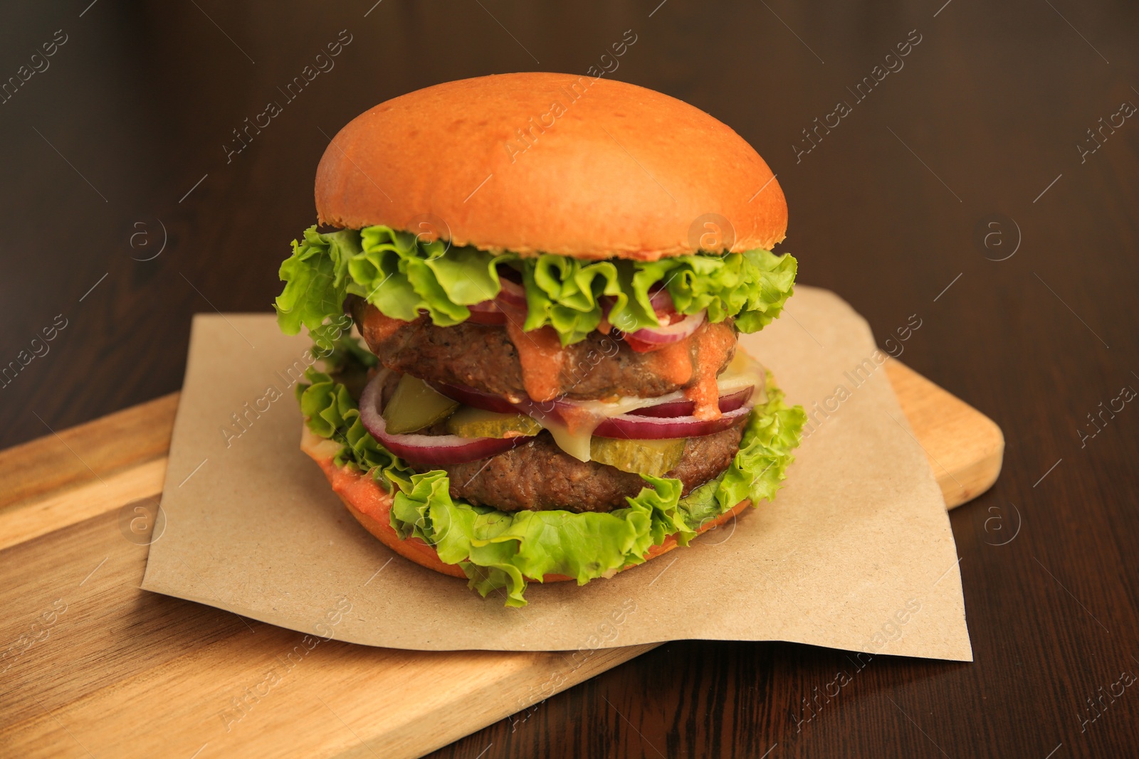 Photo of Board with tasty burger on wooden table, closeup